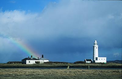 The High Lighthouse with adjacent acetylene generating house and nearby cottages, brightened by a rainbow