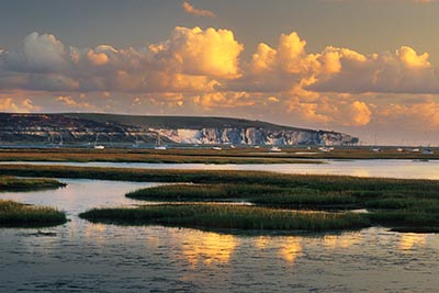 The view over the mudflats at Keyhaven, looking towards the Isle of Wight as the setting sun illuminates the clouds