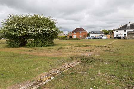 A building outline showing through the turf opposite the village post office and shop